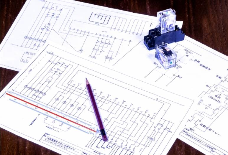 電気回路図とリレー部品。設計中の様子